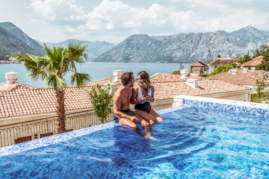 Couple relaxing in a clifftop infinity pool overlooking the bay